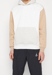 Felpa con cappuccio con un design in blocchi di colore beige e grigio chiaro. Realizzata in tessuto morbido, presenta una tasca a marsupio e un dettaglio del logo sul petto.