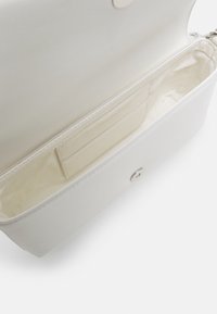 Porte-monnaie rectangulaire blanc ouvert montrant un intérieur lisse avec une petite poche à fente pour cartes cousue et une fermeture bouton magnétique.