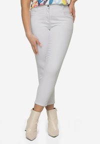 Lys grå slim-fit jeans med en glat tekstur, medium høj talje og fem-lommer design, parret med beige ankelstøvler.