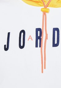Sudadera blanca con capucha que presenta letras en negrita de color azul marino "J O R D", con un cordón naranja y forro de capucha amarillo. Textura de tela suave y colores contrastantes.