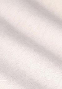 Tissu en coton beige clair avec une texture lisse et un fin motif de nervures, affichant de subtiles variations de couleur et de brillance.