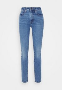 Jeans ajustados de mezclilla azul claro, con una cintura alta, cuatro bolsillos y un desvanecido mínimo. Diseño clásico de cinco bolsillos con trabillas para cinturón.
