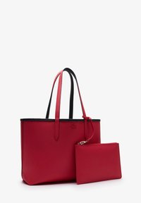 Bolso tote de cuero rojo con textura, con bordes negros y asas largas, que incluye un estuche rojo a juego con cremallera y un detalle de logotipo.
