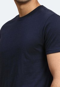 Dunkelblaue Baumwoll-T-Shirts mit Rundhalsausschnitt und kurzen Ärmeln, die eine glatte Textur und eine taillierte Passform bieten. Keine sichtbaren Logos oder Muster.