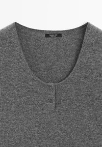 Maglione grigio in maglia con scollatura a V profonda e due bottoni frontali. Texture morbida e design casual adatto per essere sovrapposto. Etichetta visibile.