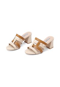 Sandali con tacco a blocco beige e marrone, caratterizzati da due ampie cinghie con disegni intagliati. Materiale in pelle liscia, stile open-toe.