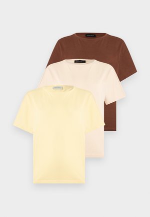 Trois T-shirts unis à manches courtes en coton empilés, de couleurs jaune, crème et marron, avec des encolures rondes et des étiquettes Anna Field.