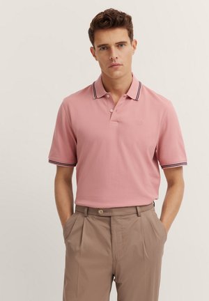 Helles rosa Polohemd mit Kragen und zwei Knöpfen, versehen mit marineblauen und weißen Streifenakzenten am Kragen und den Ärmeln. Lässige Passform.