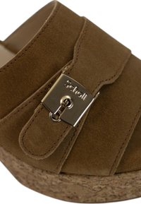 Sandalo in suede marrone con una fascia larga e una chiusura metallica, caratterizzato da una suola in sughero testurizzato. I dettagli cuciti arricchiscono il design.
