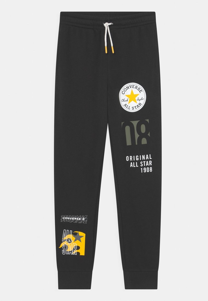 Svarta Converse träningsbyxor med vit dragsko, prydda med gula och vita All Star-logotyper och text på framsidan av benen.