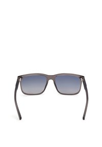 Gafas de sol con montura cuadrada, material plástico gris oscuro, lentes degradados de azul oscuro a azul claro, y patillas negras elegantes con agarre texturizado.
