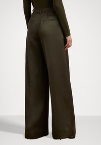Wide-leg trousers in olive green, made of smooth fabric. Features a tailored waistband, two back pockets, and a relaxed fit.