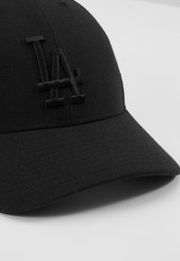 Svart caps med buet skjerm, med en brodert LA-logo, laget av teksturert stoff med en glatt finish og subtile mønstre.