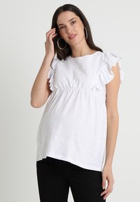 Blusa de maternidade branca com frente bordada, mangas curtas com babados e um corte descontraído. Tecido suave com decote redondo, estilo casual.