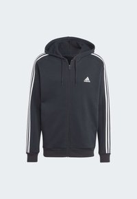 Μαύρη ζακέτα με φερμουάρ και κουκούλα, λ�ευκό λογότυπο Adidas στο στήθος και τρεις λευκές ρίγες κατά μήκος των μανικιών. Μαλακό ύφασμα, πλεκτοί καρπούς.