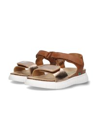 Bruine leren sandalen hebben metalen bronzen banden, verstelbare klittenbandsluitingen, een gewatteerde voetbed en een witte rubberen zool.