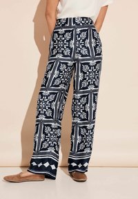 Navyblauwe wijde broek met een wit bloemen- en geometrisch patroon, met een hoge tailleband en een gladde textuur. Comfortabele instap schoenen.