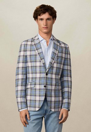 Heller, kariert Blazer in Blau, Grün und Weiß, mit einer einstelligen Knopfschluss, einfachen Revers und zwei Fronttaschen. Kombiniert mit einem gestreiften Hemd.