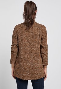 Bruine geblokte jas met een gestructureerde stof, voorzien van een dierenprintdesign, lange mouwen en een licht gebogen zoom aan de achterkant.