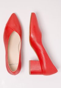 Ein Paar rote Leder-Blockabsatzschuhe, einer von oben und der andere von der Seite auf einem weißen Hintergrund gezeigt.