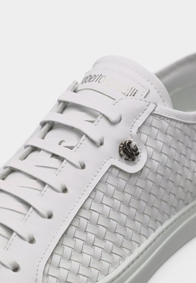 Baskets blanches avec côté en cuir tressé, lacets blancs, détail logo en métal et nom de la marque imprimé sur la languette.