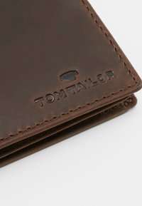 Braune Lederbörse mit geprägtem "TOM TAILOR"-Logo, ausgestattet mit einer strukturierten Oberfläche und kontrastierenden Nähten entlang der Kanten.