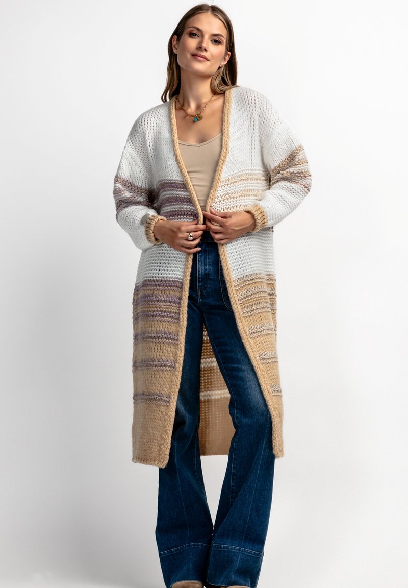 Sweter na drutach w kolorze białym z beżowymi i lawendowymi paskami. Otwarty przód, długie rękawy i luźny krój, zestawiony z niebieskimi dzwonami.