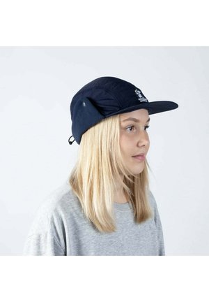 Tummansininen hattu, jossa on litteä lippa, fleece-korvaläpät ja logo edessä. Siinä on pörröinen kangas ja säädettävä leukahihna.