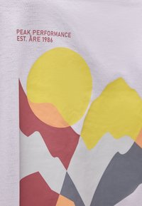 Γραφικό αφηρημένων βουνών σε κόκκινο, κίτρινο, γκρι και ροδακινί με κείμενο «Peak Performance Est. Åre 1986» πάνω σε ανοιχτό φόντο υφάσματος.