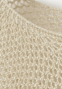 Beżowa luźno tkana tkanina o siateczkowym, otwartym wzorze szydełkowym z subtelnymi metalicznymi nitkami tworzącymi teksturowaną powierzchnię.