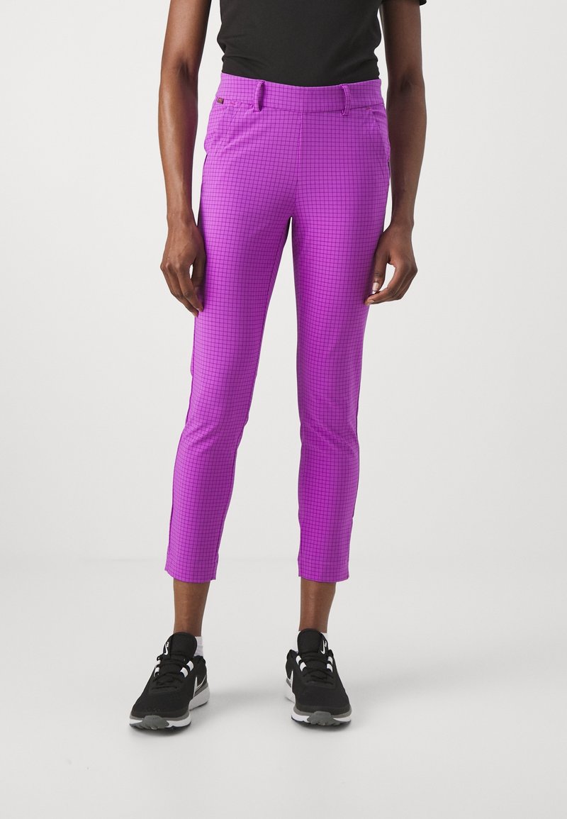 Person wearing purple slim fit cropped pants with a subtle grid pattern and black sneakers against a plain white background.