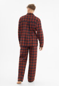 Punaiset ja tummansiniset ruudulliset flanelli pyjamat, joissa on nappipaita ja löysät housut, jotka sisältävät pitkät hihat ja hienovaraisen tekstuurin.