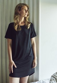 Vestido negro de manga corta, hecho de una tela suave, con cuello redondo y un ajuste relajado, con un dobladillo ligeramente curvado.