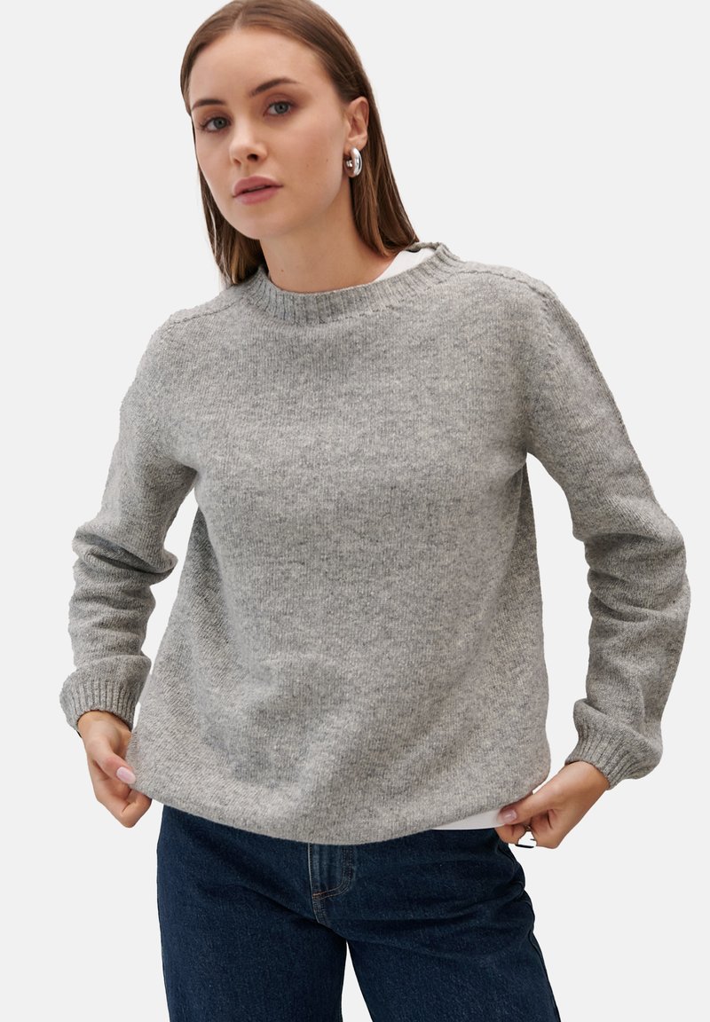Szary sweter z dzianiny z długimi rękawami i okrągłym dekoltem. Prążkowane mankiety i dół. Nosi się na białej bluzce i w połączeniu z ciemnym dżinsami.