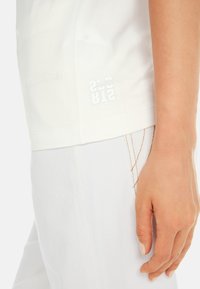Witte katoenen t-shirt met een ontspannen pasvorm, voorzien van een gestikte zoom. MarcCain-logo in een contrasterende glanzende print aan de zijkant.