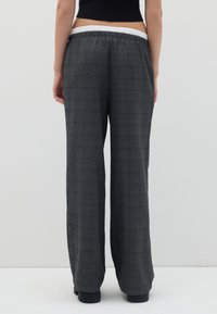 Brede broek in grijs geruit stof met een elastische witte taille. Het materiaal heeft een zachte textuur en een losse pasvorm, geschikt voor casual draagstijl.