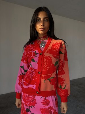 Rød og rosa cardigan med rose-mønster, har rund hals, knappelukking og ribbestrikkede ermer. Brukes over en matchende blomsterkjole.