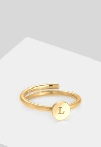 Goldring mit einem geteilten Banddesign; zeigt eine runde Scheibe mit einem geprägten Buchstaben "L". Glatte Textur mit polierter Oberfläche.