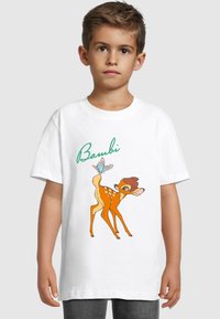 Bílá bavlněná tričko s barevnou ilustrací Bambiho, s zeleným textem "Bambi" nad postavou. Krátké rukávy a volný střih.