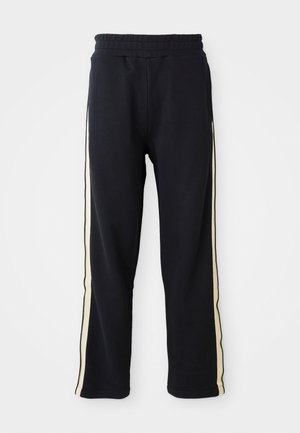 Črne trenirke z elastičnim pasom, ki imajo svetlo kremaste črte ob straneh. Narejene iz mehkega, teksturiranega materiala.