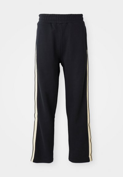 Zwarte joggingbroek met een elastische tailleband, voorzien van crèmekleurige strepen aan de zijkanten. Gemaakt van een zachte, gestructureerde stof.
