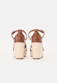 Sandales compensées en cuir brun avec une semelle intermédiaire en jute tissé, des sangles de cheville réglables et une semelle texturée avec un motif en relief.