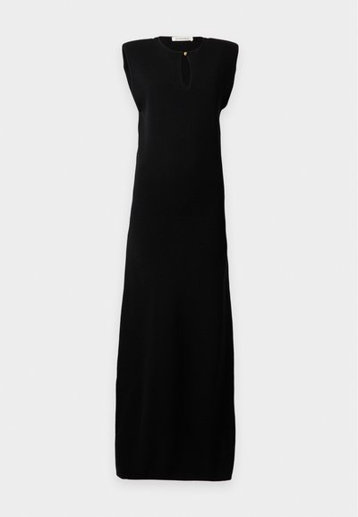 Longue robe noire sans manches avec des épaulettes et une petite ouverture en forme de goutte à l'avant, fermée par un seul bouton au niveau du col.