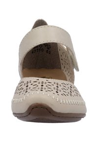 Scarpa slip-on beige con tomaia in pelle perforata, dettagli cuciti, cinturino regolabile e suola a profilo basso. Texture morbida e forma arrotondata.