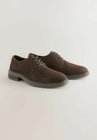 Chaussures en suède marron avec un bout rond, un design à lacets et des accents gris avec des coutures contrastées sur une semelle en caoutchouc.