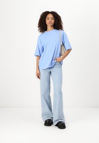 Ljusblå oversized t-shirt med korta ärmar, matchad med ljusblå utsvängda jeans och svarta plattformsskor. Har en avslappnad och komfortabel passform.