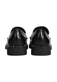 Scarpe in pelle nera con una finitura liscia, punta arrotondata e dettagli borchiati lungo la suola. Design a profilo basso con tacco piatto.