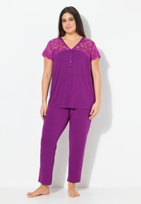Paarse pyjama set met korte kantmouwen top en bijpassende broek. Beschikt over een V-hals met knopen, zachte stof en een losse pasvorm.