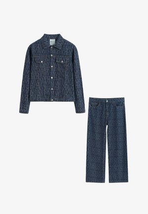 Veste en denim et jean droit bleu foncé avec motif de texte répétitif et boutons blancs.