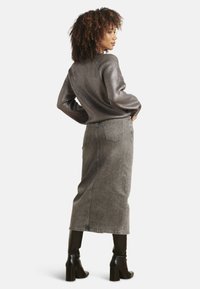 Grijs geribbeld sweater met lange mouwen gecombineerd met een hoog in de taille gesneden grijze denim rok. Zwarte kniehooglaarzen. Eenvoudige, strakke lijnen en texturen.